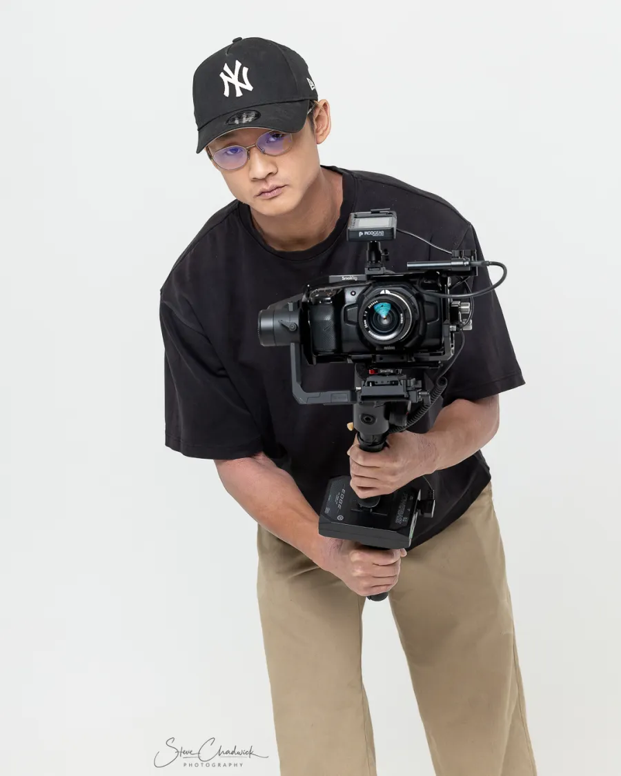 Filmmaker in a cap leaning over a gimbal-mounted cinema camera in a studio